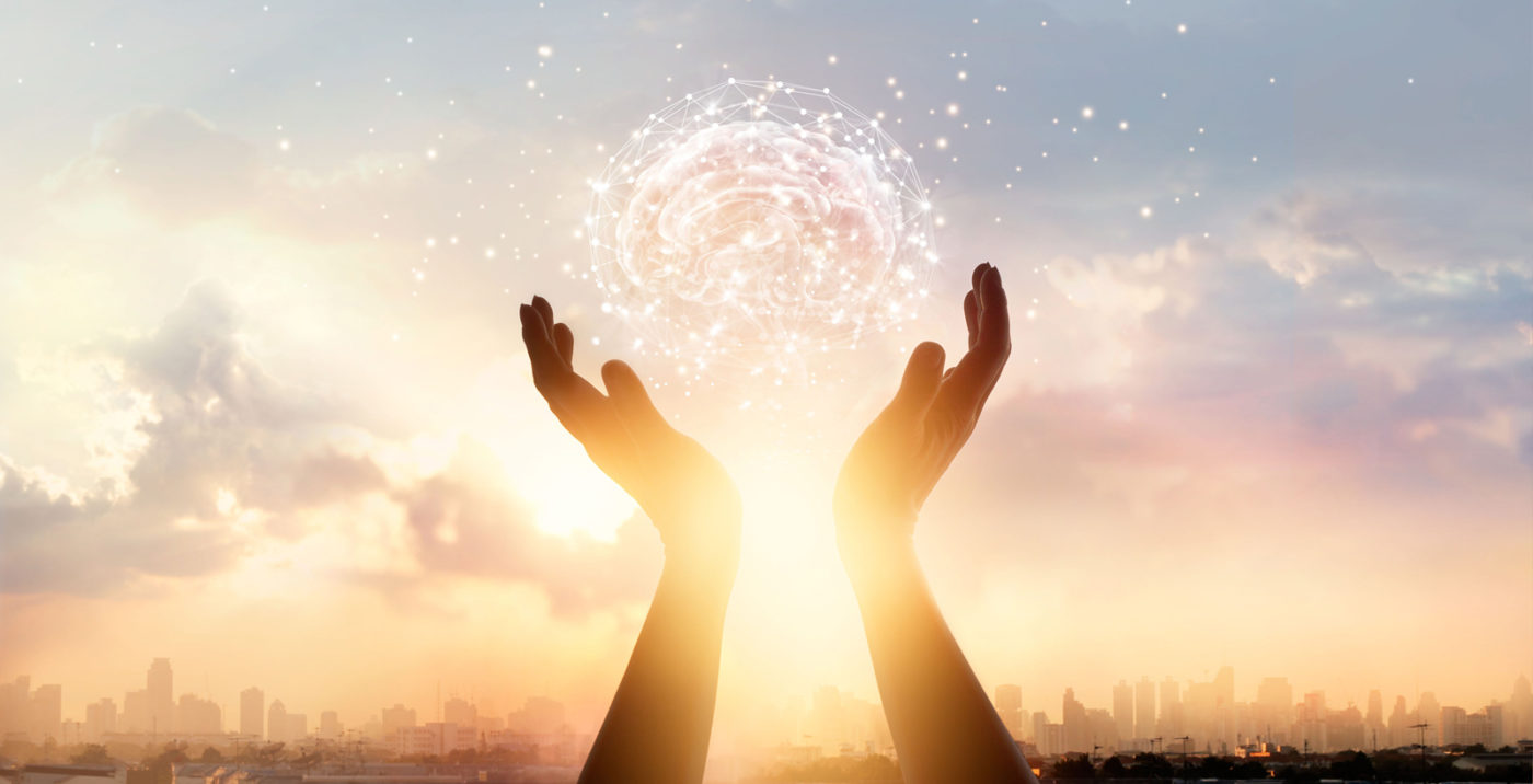Two hands hold a digital image of a brain. The sun is shining in the sky.